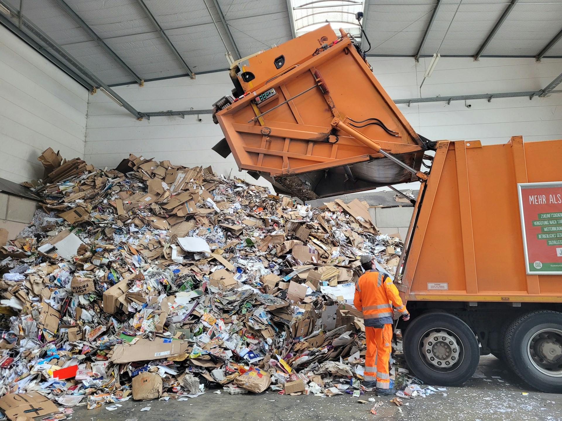 Industrial waste collection truck lifting a dumpster in a city alleyway, showcasing the hidden machinery behind waste disposal.